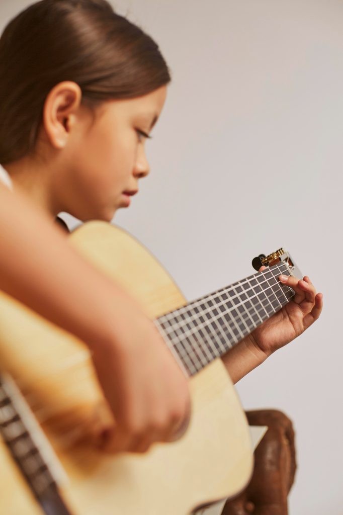 petite fille apprenant jouer guitare maison